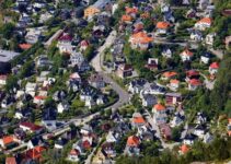 Flyfoto av tett boligområde med hus, hager, veier og jernbane