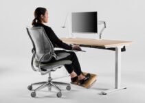 Person ved ergonomisk hjemmekontor med hev-senk-pult og skjerm