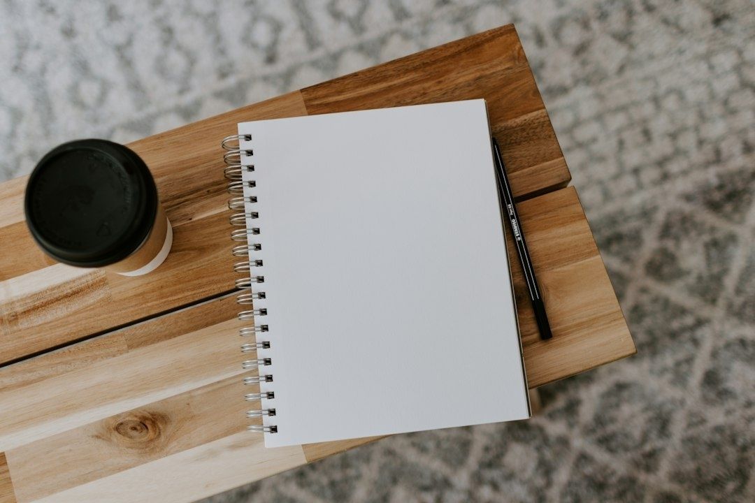 Blank notatbok, penn og kaffekopp på et trebord